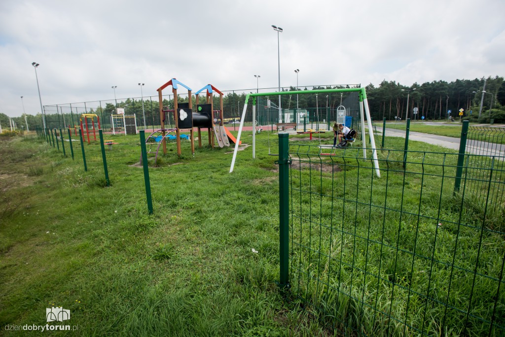 Plac zabaw z wysoką trawą i bez ogrodzenia