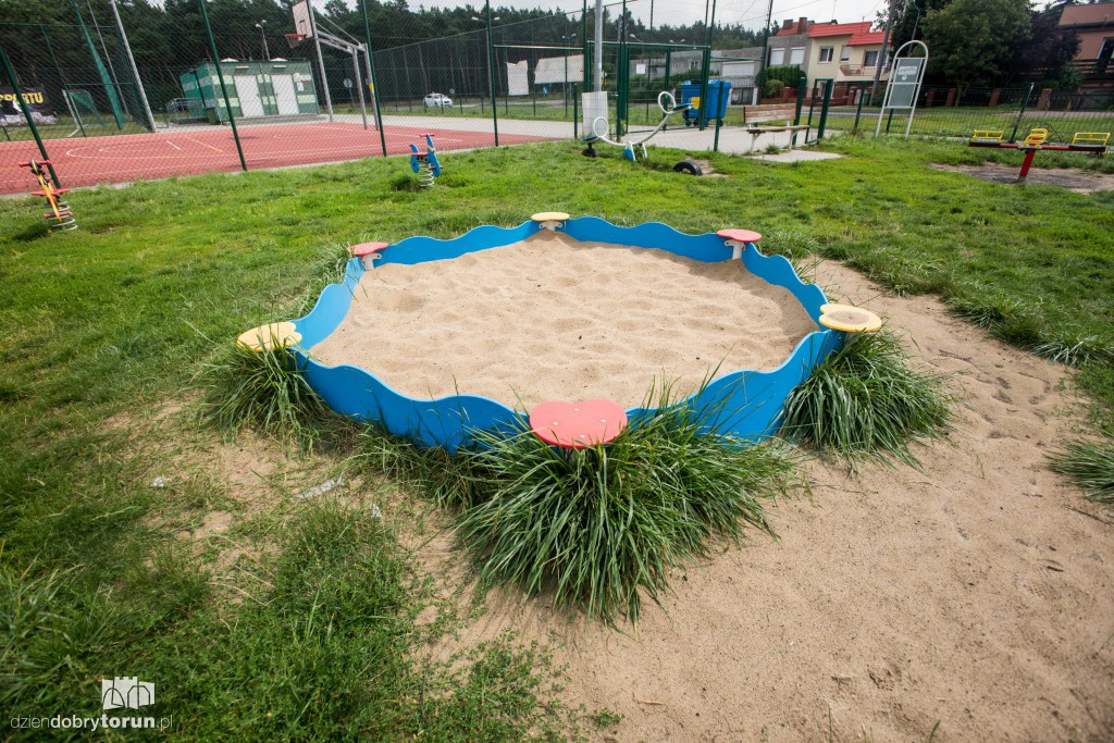 Plac zabaw z wysoką trawą i bez ogrodzenia