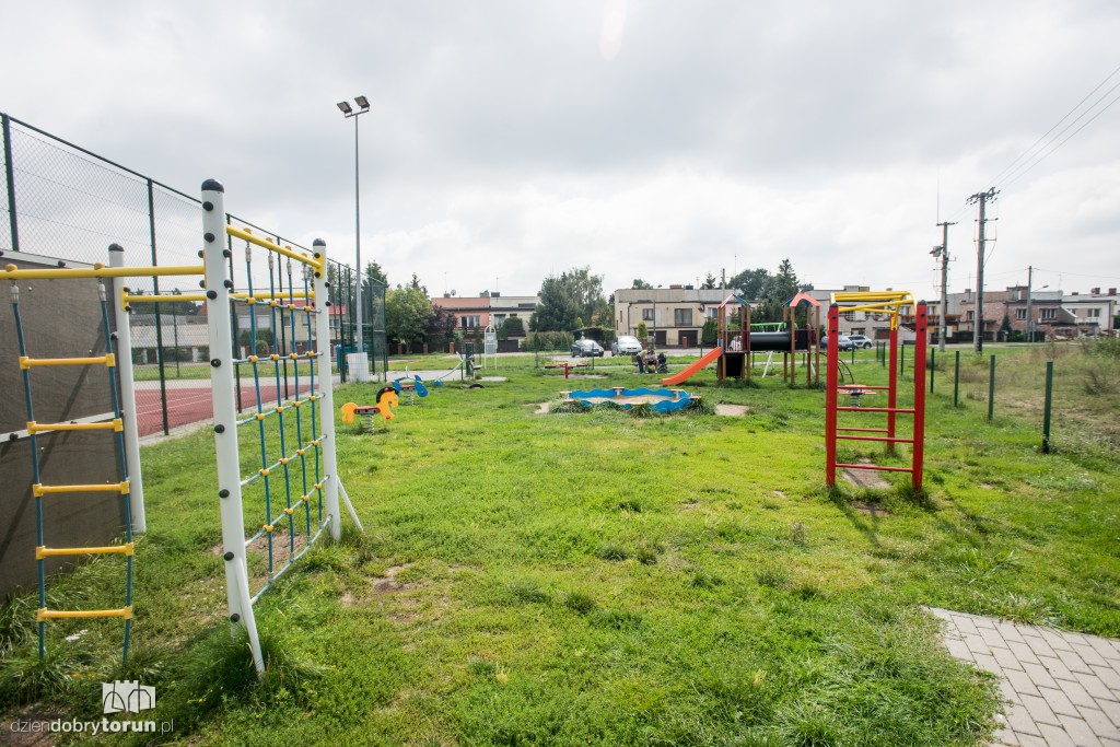 Plac zabaw z wysoką trawą i bez ogrodzenia