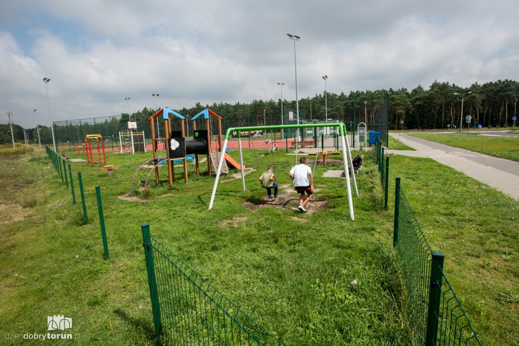 Plac zabaw z wysoką trawą i bez ogrodzenia