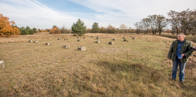 Tomasz Iwaszkiewicz prezentuje betonowe podmurówki jenieckich baraków (fot. Tomasz Berent)