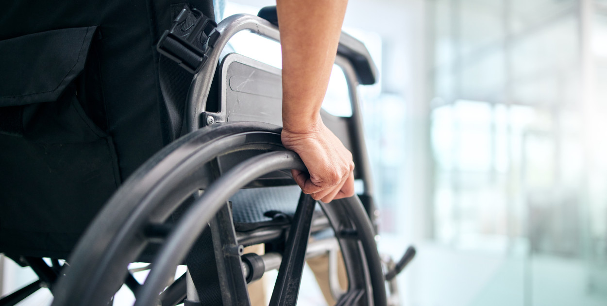 Ręka na kole wózka inwalidzkiego. Zdjęcie ilustracyjne. Depositphotos